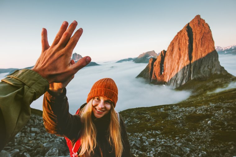 Blid jente på fjelltur gir high five