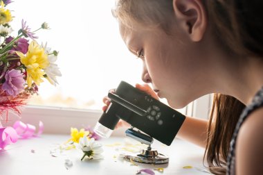 Jente sitter og studerer blomster