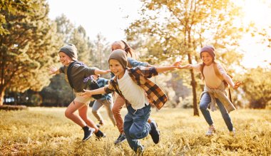 Smilende barn løper ute i høstfarger