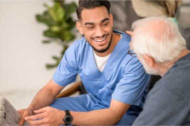 Mannlig pleier snakker med eldre pasient