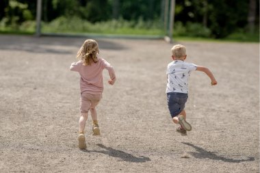To barn løper bortover en grusvei